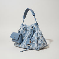 Blue plaid denim handbag with braided handle and attached mini pouch on beige background