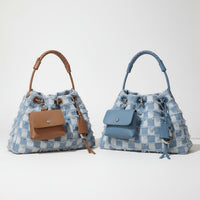 Two blue textured bucket bags with attached brown and blue pouches on neutral background