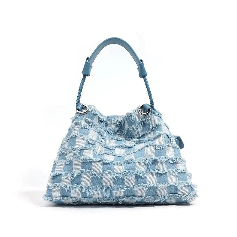 Light blue checkered denim handbag with frayed edges and braided handle on white background