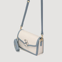 Cream and blue crossbody bag with bunny accent and matching pouch on gray background