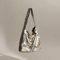 Beige canvas shoulder bag with black geometric pattern on a wooden chair