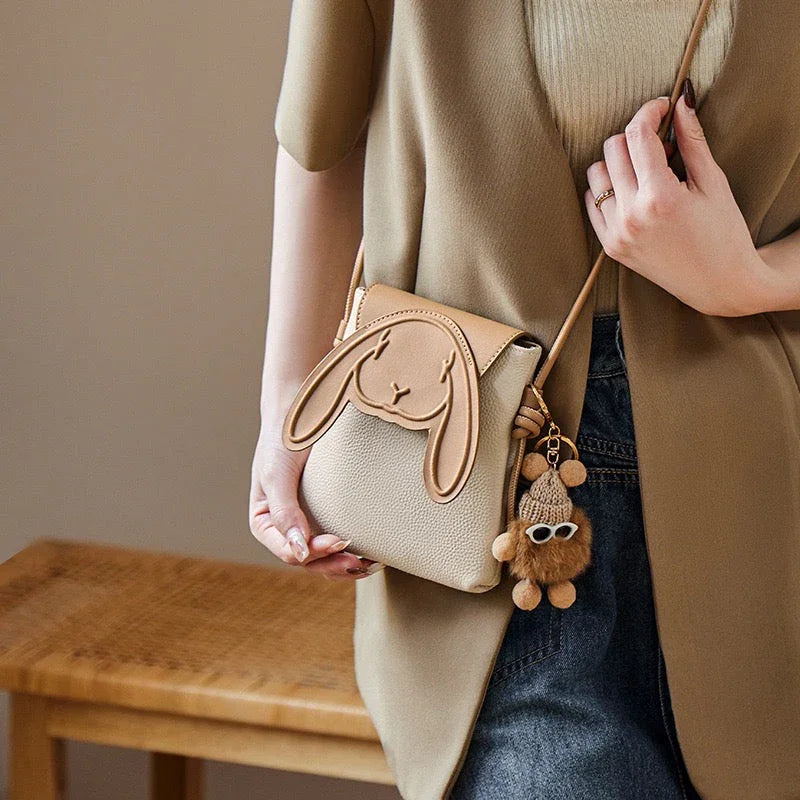 Woman wearing beige bunny crossbody bag with plush keychain, casual outfit fashion