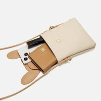 Beige leather crossbody bag with gold snap, holding a phone, wallet, and lipstick.