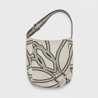 Woman wearing sleeveless beige buttoned dress with large patterned canvas crossbody bag