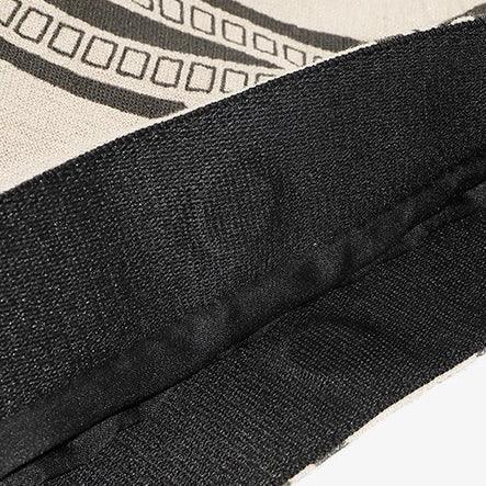 Close-up of black fabric hem with beige cloth and geometric print pattern