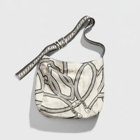 Beige shoulder bag with black and grey geometric line patterns on a tan background