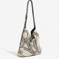 Beige canvas shoulder bag with black geometric chain pattern and adjustable strap