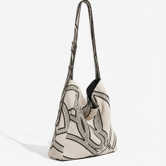 Beige canvas shoulder bag with black geometric chain pattern and adjustable strap