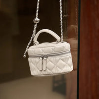 White quilted mini handbag with zipper and chain strap, luxury purse on display