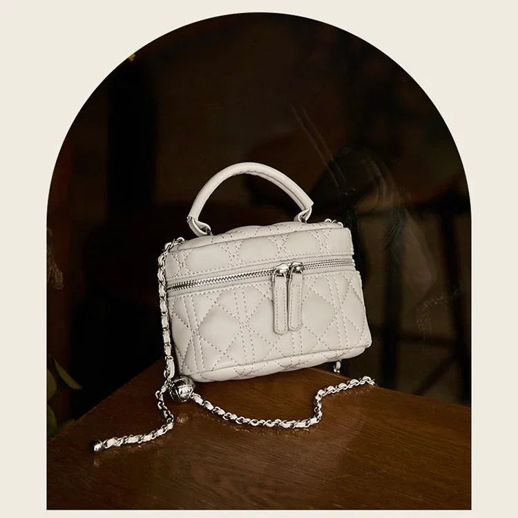 Quilted white leather mini handbag with chain strap on wooden table