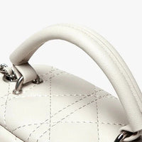Close-up of white quilted leather handbag handle with silver hardware on a light background