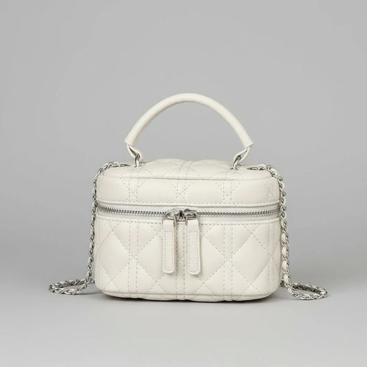 Quilted white leather handbag with top handle, silver chain strap, and front zipper on gray background