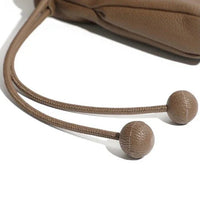 Brown leather drawstring bag with knotted ends on a white background