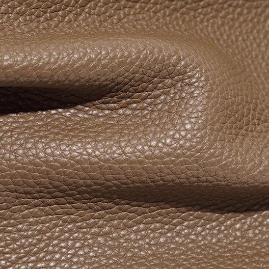 Close-up of textured brown pebbled leather material with natural fold and grain detail