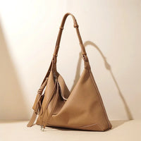 Beige leather hobo handbag with adjustable strap on neutral background