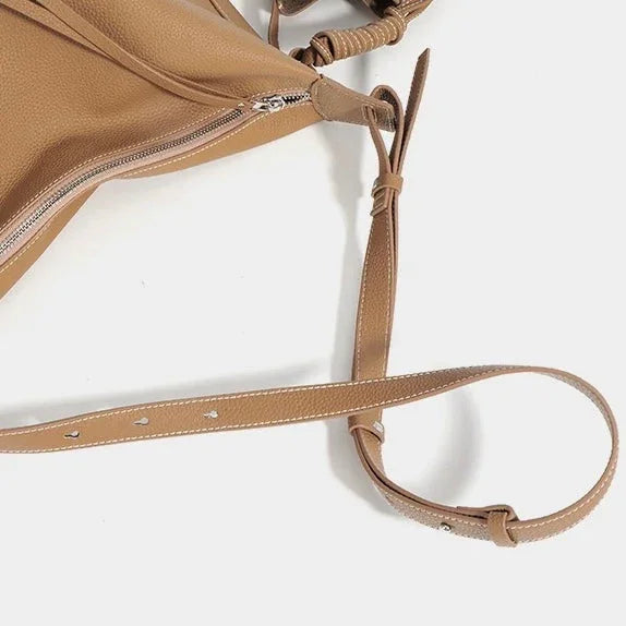Tan faux leather shoulder bag with adjustable strap and zipper on white background