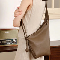 Woman in beige dress wearing brown leather shoulder bag, vintage radio in background