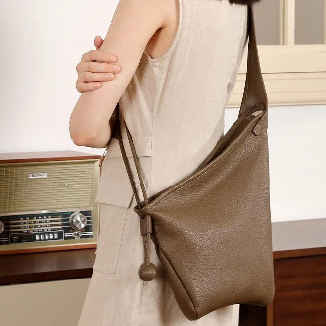 Woman in beige dress wearing brown leather shoulder bag, vintage radio in background