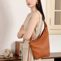 Woman in beige dress with large brown leather shoulder bag in vintage-style room