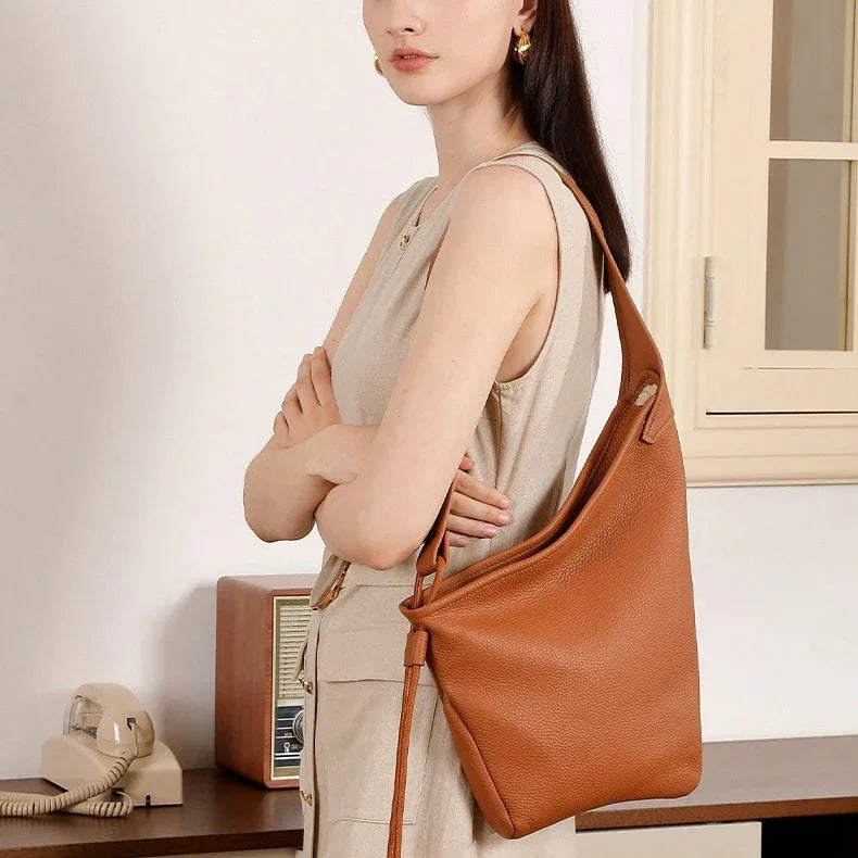 Woman in beige dress with large brown leather shoulder bag in vintage-style room