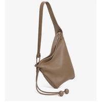 Taupe leather sling bag with adjustable strap and drawstring accents on white background