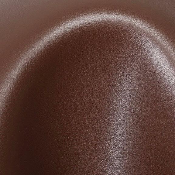 Close-up of smooth brown leather surface with curved indentation and light reflection