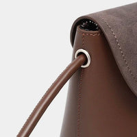 Close-up of brown leather handbag with silver grommet and stitching detail
