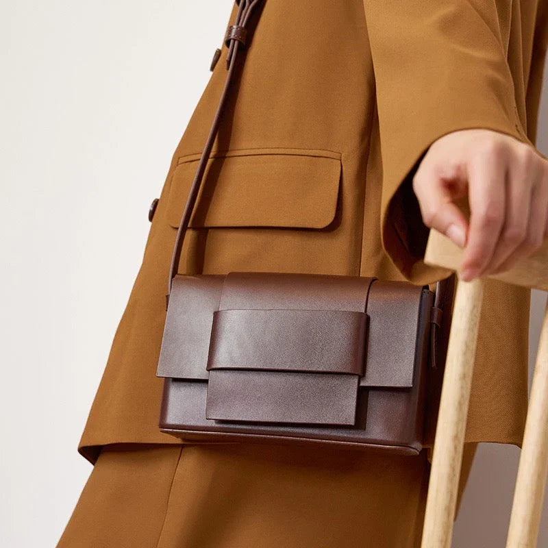 Woman in brown suit holding modern dark brown leather crossbody bag