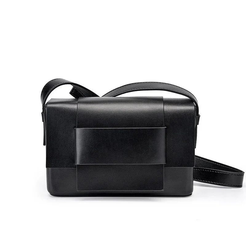 Sleek black leather crossbody bag with wide strap, minimalist design, on white background