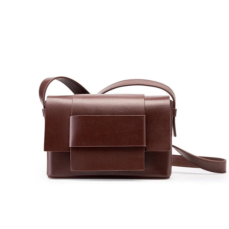 Brown leather crossbody bag with geometric flap design on white background