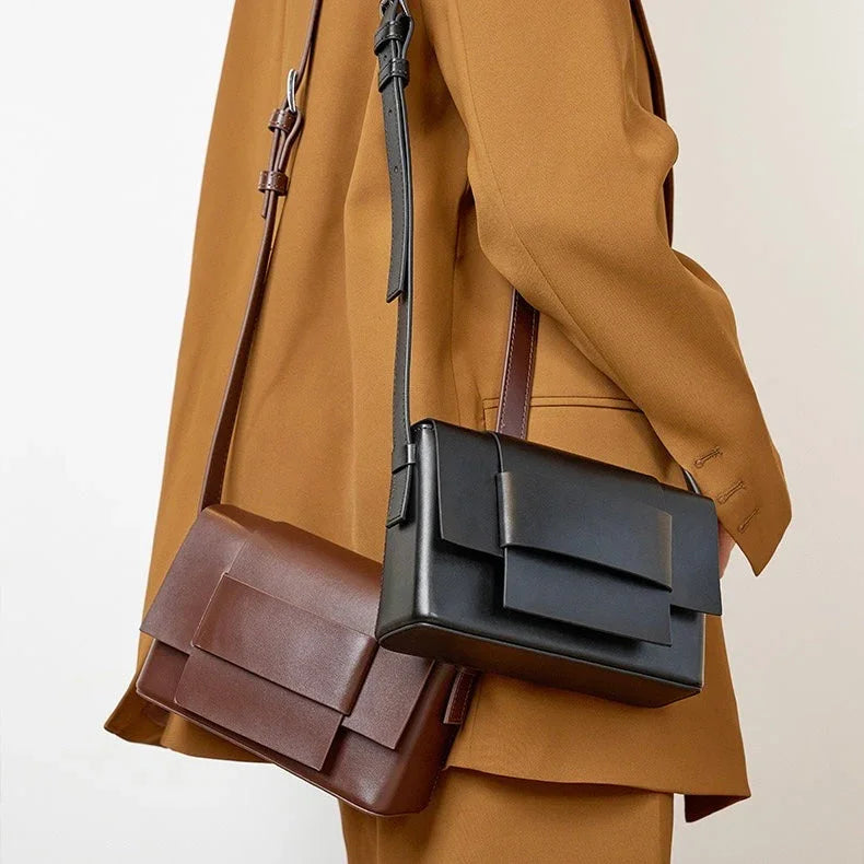 Woman in brown suit with black and brown leather crossbody handbags