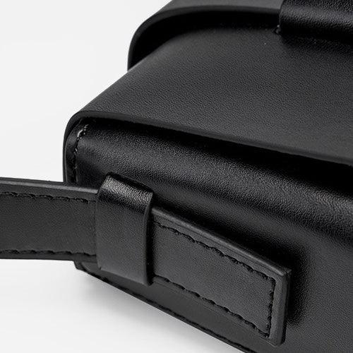 Close-up of black leather crossbody bag with stitched strap and minimalist design