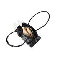 Black leather handbag with zippered opening and beige interior on white background