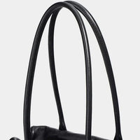 Close-up black leather handbag handles against a white background