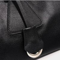 Close-up of black leather handbag with silver buckle detail