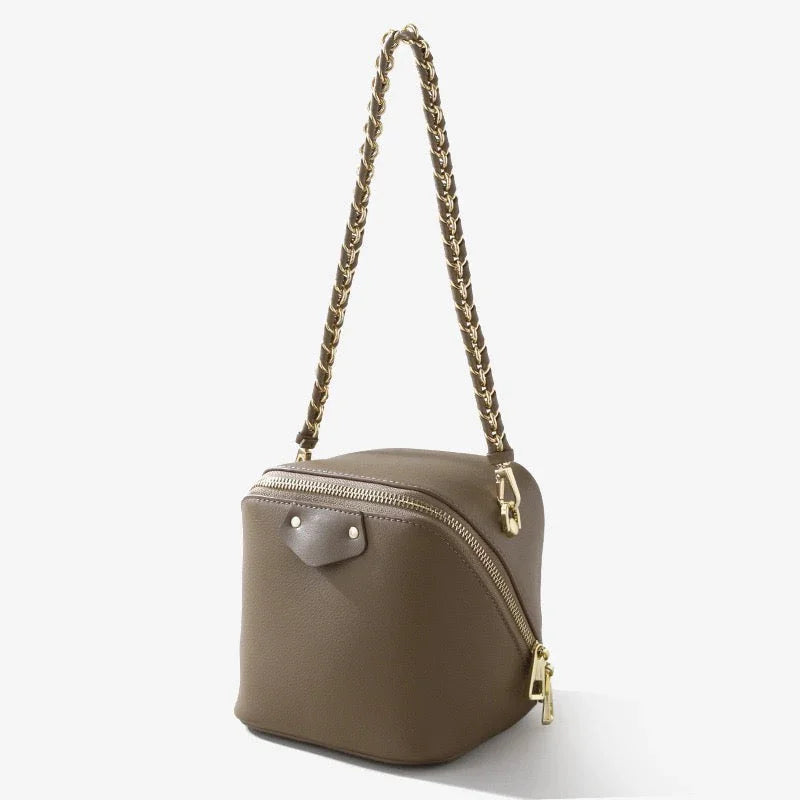 Taupe leather box bag with gold chain strap and zipper, stylish cube purse on white background