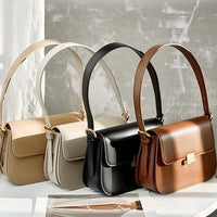 Three leather shoulder bags in beige, black, and brown on a light surface with sunlight.