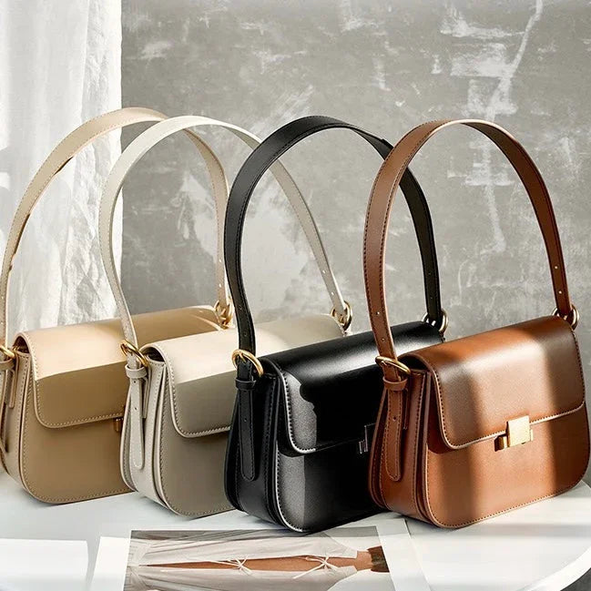 Three leather shoulder bags in beige, black, and brown on a light surface with sunlight.