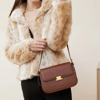 Woman in faux fur jacket with brown leather shoulder bag and gold clasp