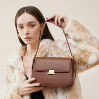 Woman in faux fur coat holding brown leather shoulder bag with gold clasp