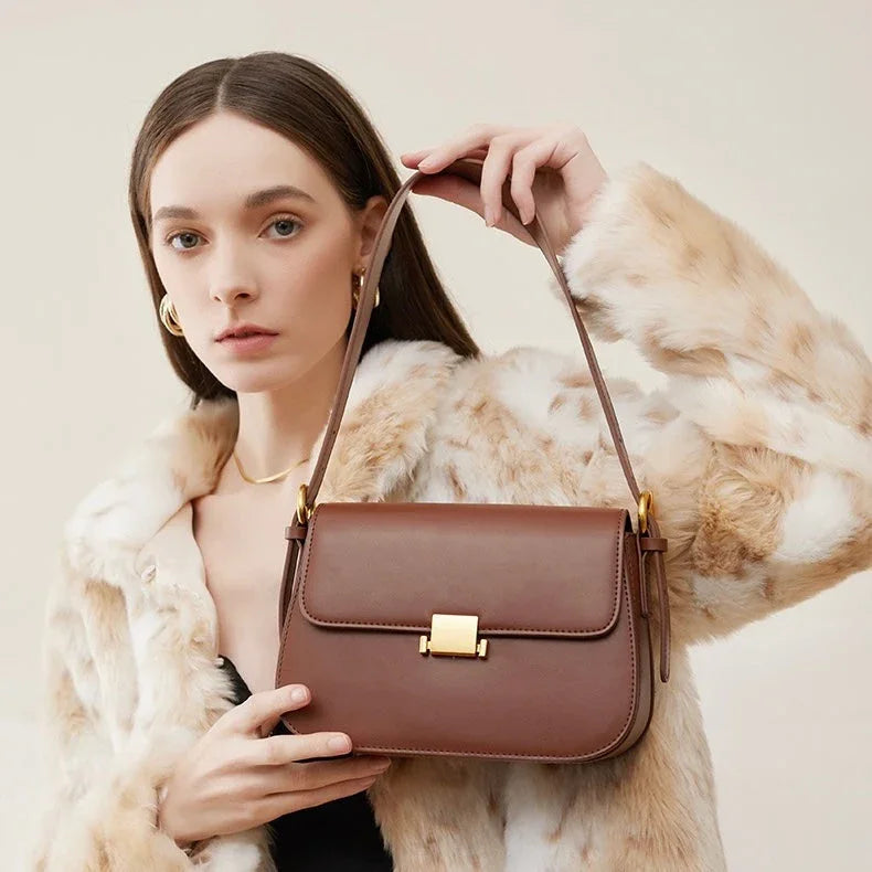 Woman in faux fur coat holding brown leather shoulder bag with gold clasp