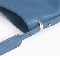 Blue leather shoulder bag with adjustable strap and silver buckle on white background