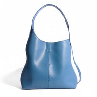 Blue leather shoulder bag with single wide strap and minimalist design on white background