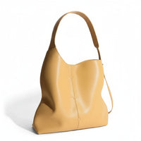 Yellow leather tote bag with wide shoulder strap on white background