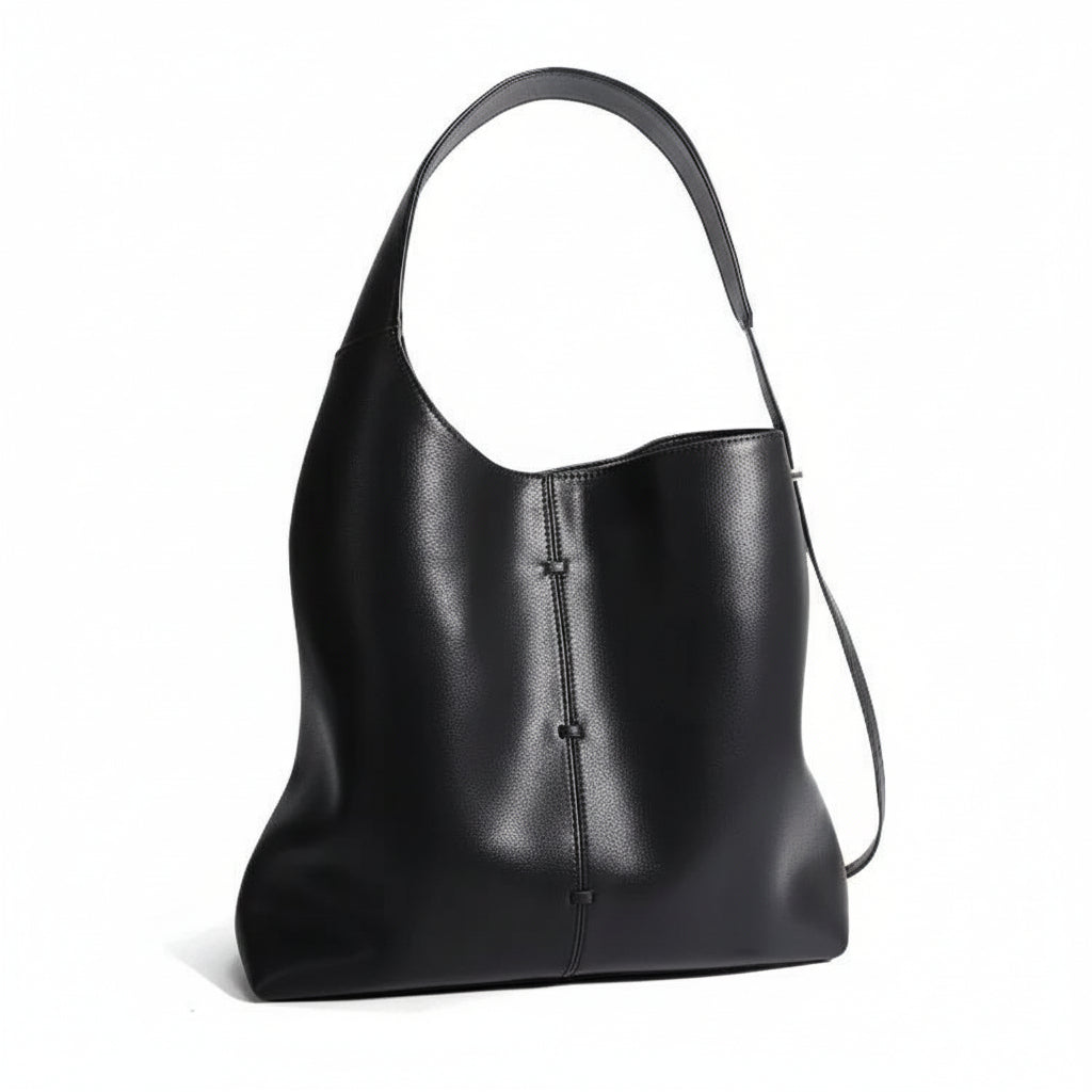 Black leather shoulder bag with single strap and minimalist stitch detail on white background