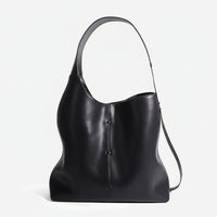 Black leather hobo bag with wide shoulder strap and minimalist seam detail, studio background