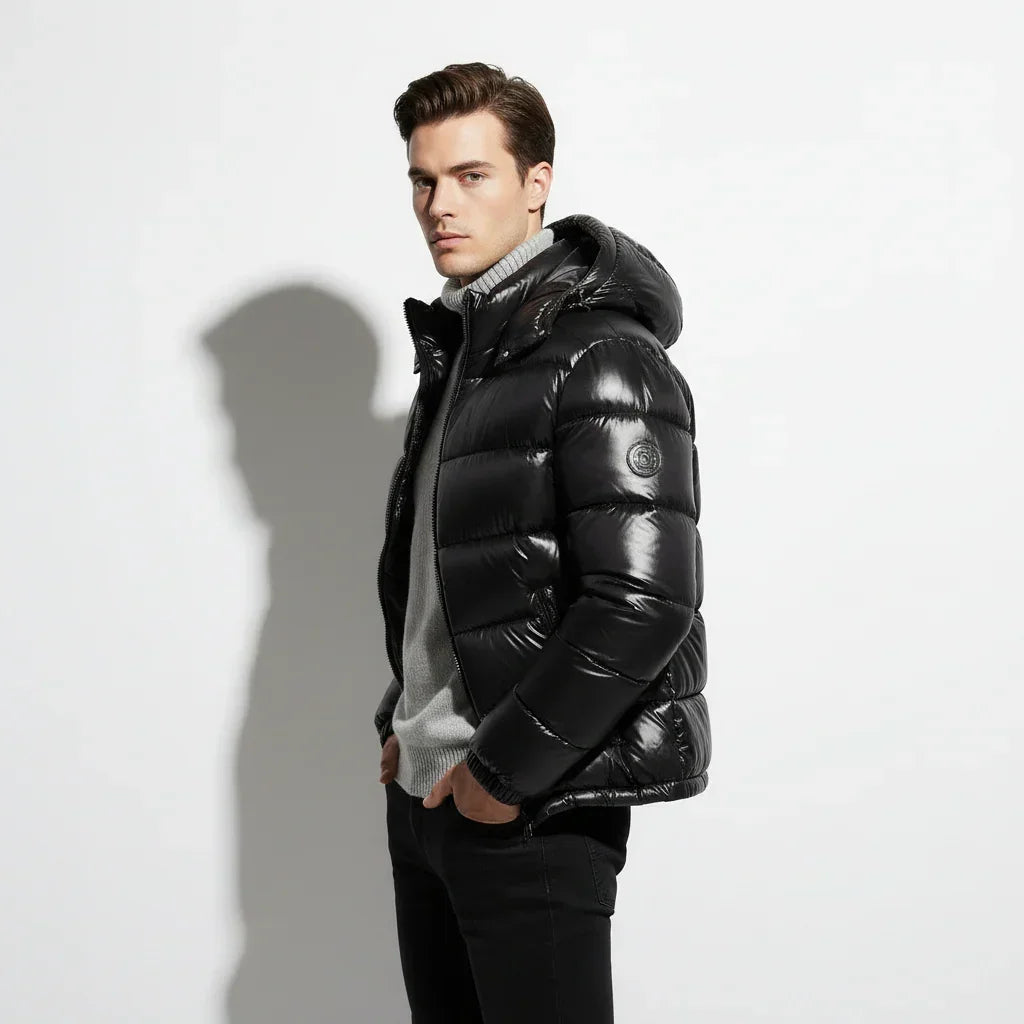 Man wearing a black puffer jacket over a gray sweater on a white background