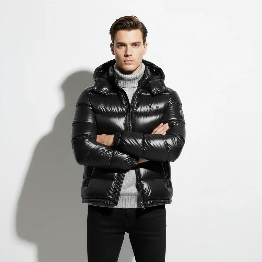 Man wearing a black puffer jacket over a gray sweater on a white background