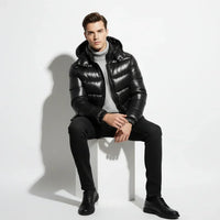 Man wearing a black puffer jacket over a gray sweater on a light gray background