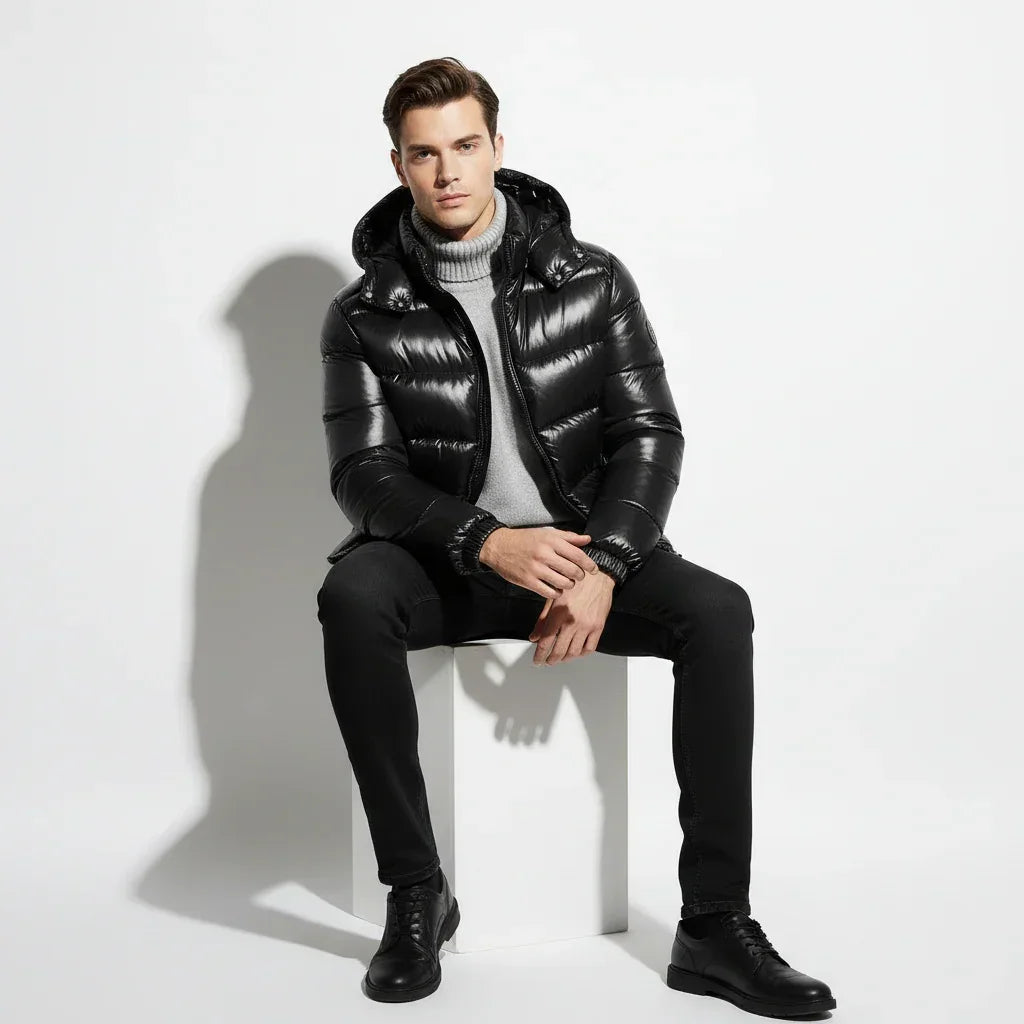 Man wearing a black puffer jacket over a gray sweater on a light gray background